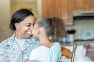 Mother in uniform and her daughter sharing a moment in the kitchen, showing transitioning to civilian life from active duty.