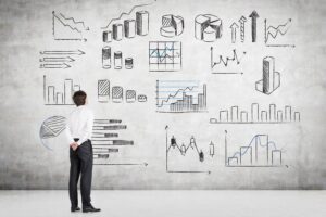 Image of a man standing pensively in front of a lot of charts and graphs, representing the power of business data analytics