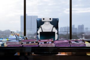 Robot sitting at a desk with a skyline behind it, representing rpa developer in DoD.
